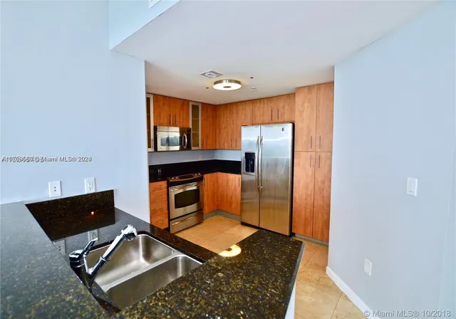 a living room with stainless steel appliances furniture a rug and a window