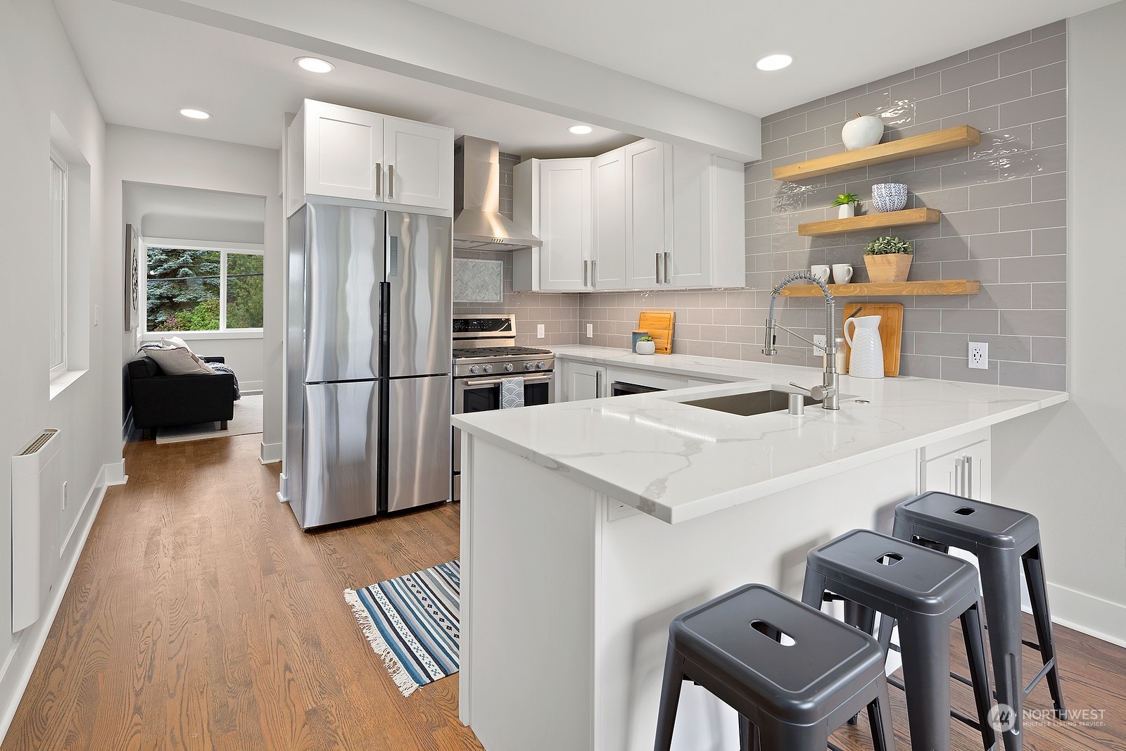 8510 Wallingford Avenue North, Unit A Seattle, WA 98103 - Photo 8 of 36 a kitchen with a refrigerator a stove a sink dishwasher and a dining table with wooden floor
