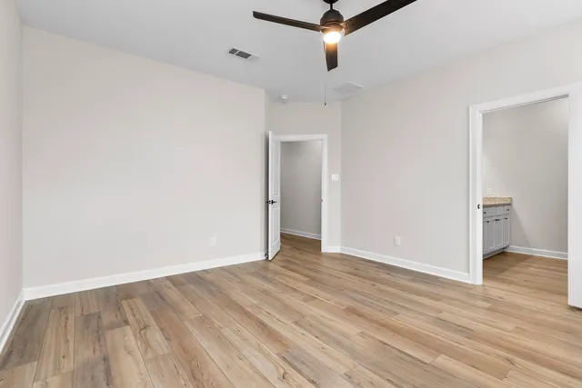 an empty room with wooden floor and a ceiling fan