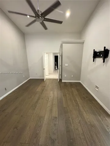 an empty room with wooden floor and ceiling fan