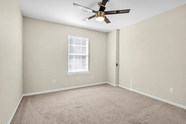 an empty room with a window and a fan