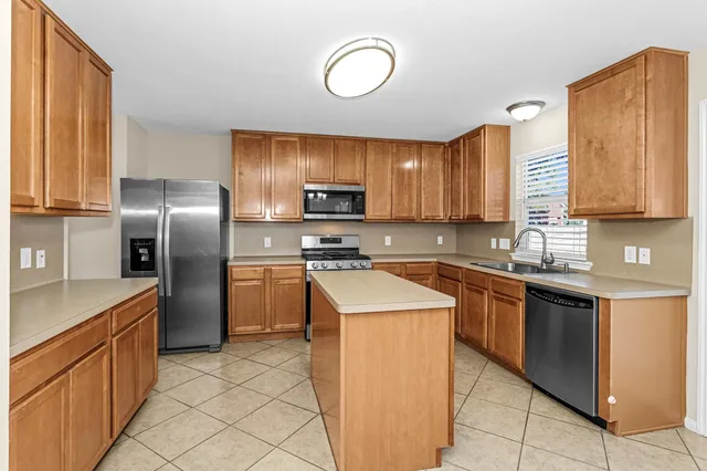 a kitchen with stainless steel appliances granite countertop a sink a stove a refrigerator and a microwave