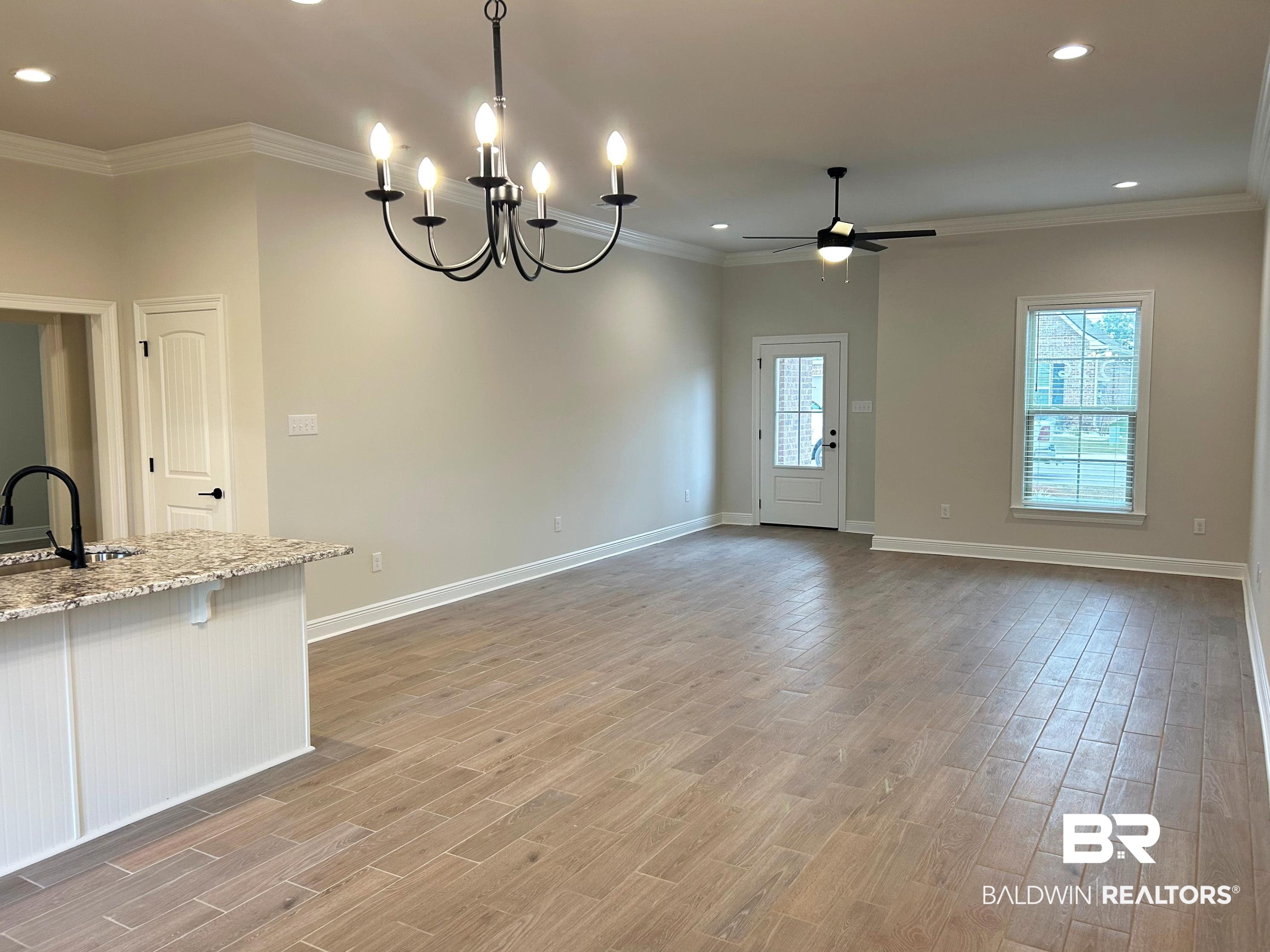 873 Sumter Loop Foley, AL 36535 - Photo 6 of 26 Kitchen featuring light stone countertops, crown molding, recessed lighting, wood finish floors, and a breakfast bar area