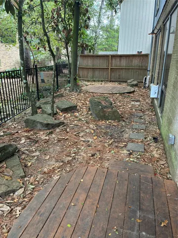 a view of a backyard with large trees and wooden fence