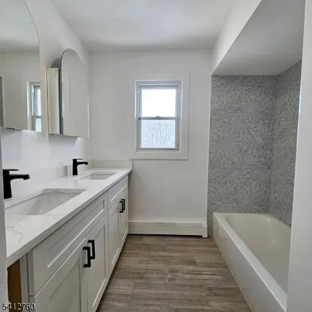 a spacious bathroom with a granite countertop sink a bathtub a mirror and vanity