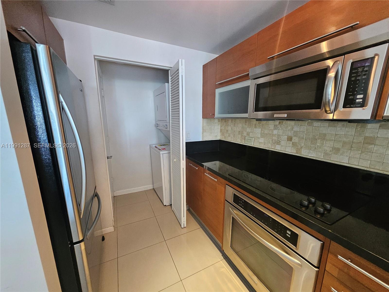 253 Northeast 2nd Street, Unit 905 Miami, FL 33132 - Photo 3 of 20 a kitchen with granite countertop a refrigerator and a stove top oven