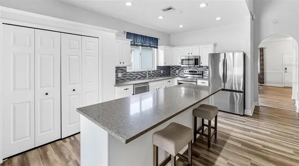 a kitchen with stainless steel appliances granite countertop a stove a refrigerator a sink a dining table and chairs