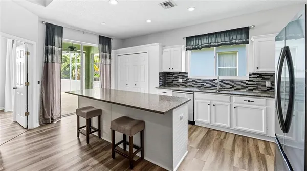 a kitchen with granite countertop a stove and white cabinets with wooden floor