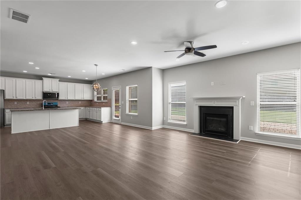 9120 Alden Drive Locust Grove, GA 30248 - Photo 17 of 39 an empty room with wooden floor kitchen view and a fireplace