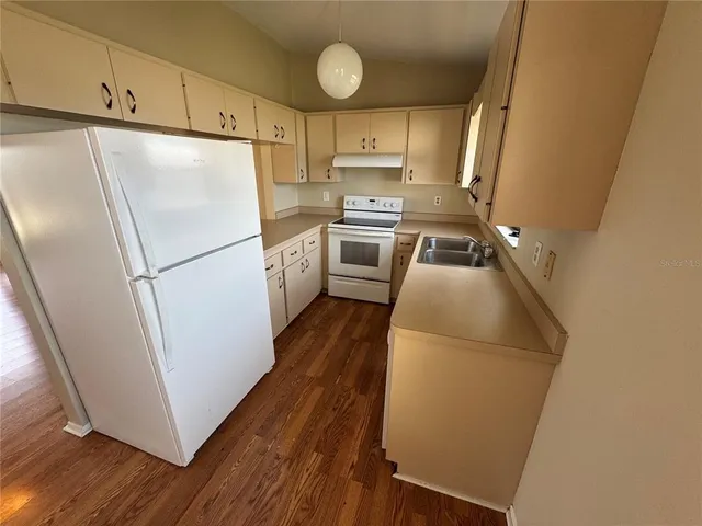a kitchen with a refrigerator a stove and wooden floor