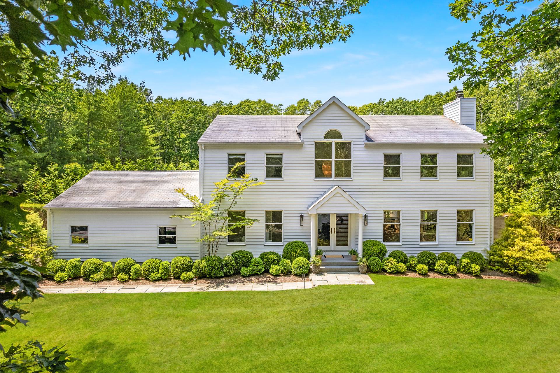 a front view of a house with a yard and trees