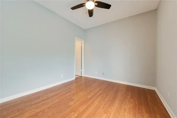 an empty room with wooden floor and chandelier fan