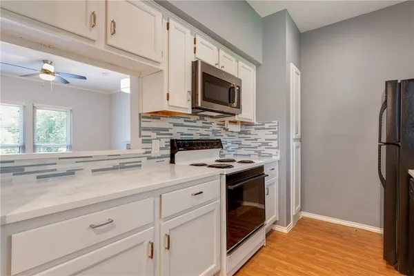 a kitchen with stainless steel appliances white cabinets a stove top oven a sink and dishwasher