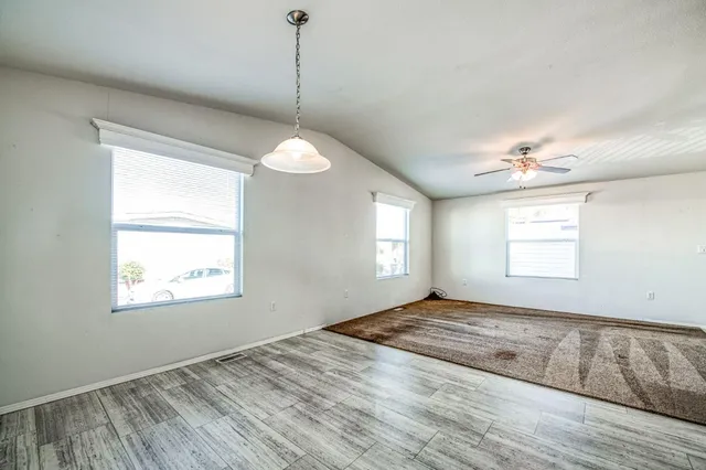 a view of an empty room with window and wooden floor