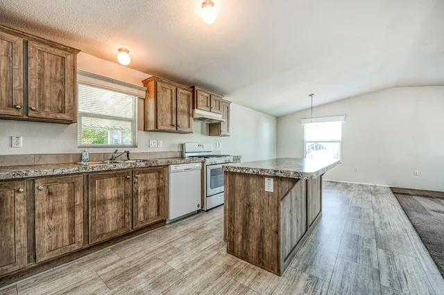 a kitchen with stainless steel appliances granite countertop a stove a sink dishwasher and a microwave oven with wooden floor