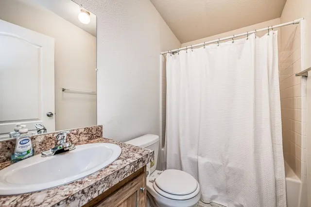 a bathroom with a granite countertop sink toilet and shower