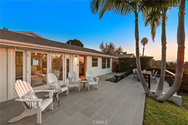 a view of a patio with dining table and chairs under an umbrella with palm trees