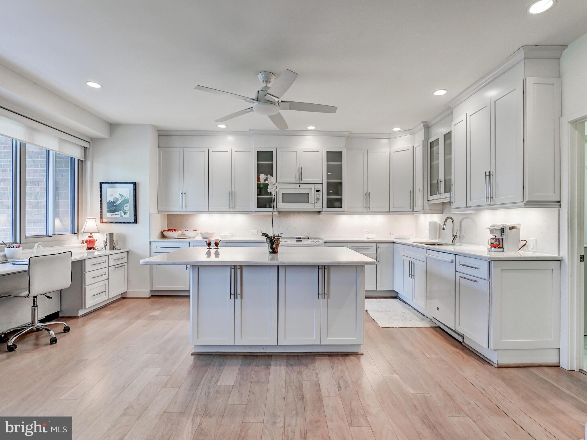11 Slade Avenue, Unit 410 Pikesville, MD 21208 - Photo 7 of 32 a large kitchen with cabinets wooden floor white stainless steel appliances and cabinets