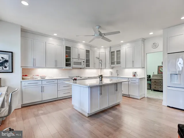 a large kitchen with cabinets wooden floor white stainless steel appliances and cabinets