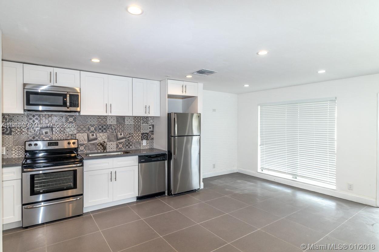 2201 Northeast 14th Avenue, Unit 3 Wilton Manors, FL 33305 - Photo 20 of 27 a kitchen with stainless steel appliances granite countertop a stove and a refrigerator