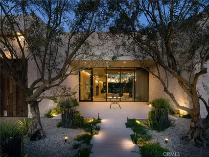 a view of the patio with dining table and chairs under an umbrella with large trees