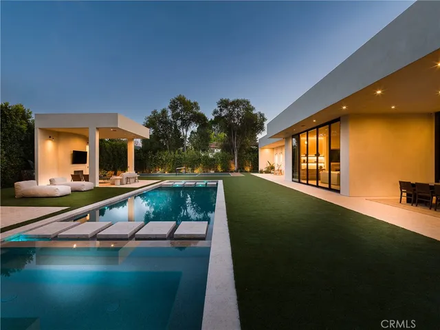 a white building with swimming pool and next to a yard