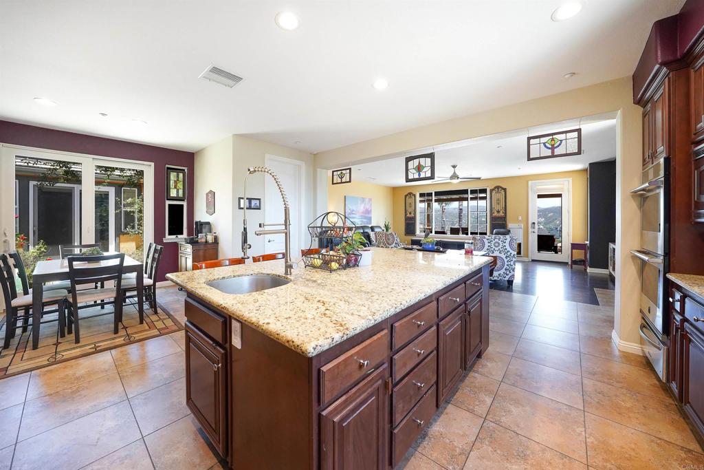 22963 Stokes Road Ramona, CA 92065 - Photo 25 of 57 a large kitchen with kitchen island a sink a counter and a view of living room