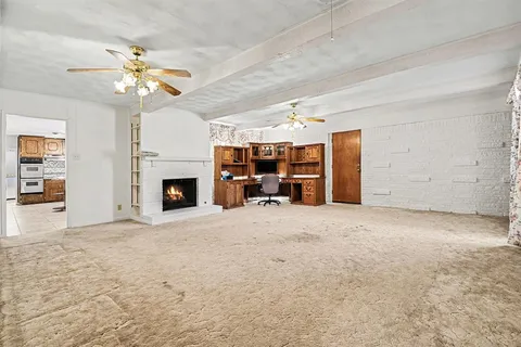 a view of a livingroom with a fireplace a chandelier fan and wooden floor