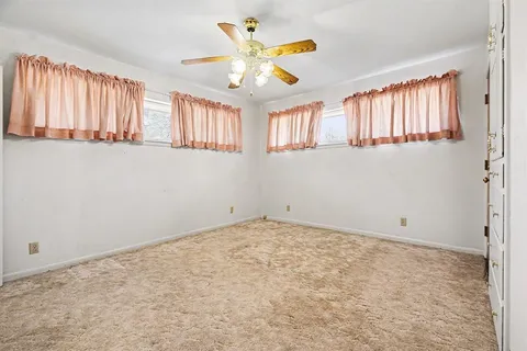 an empty room with a window and a ceiling fan