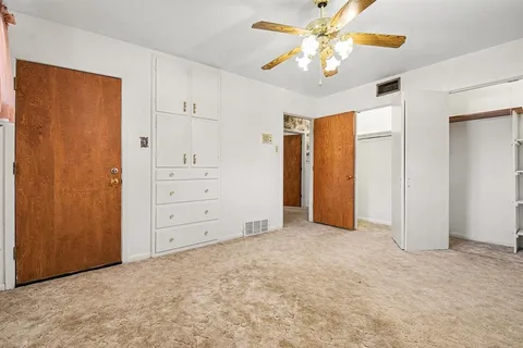 an empty room with closet and a ceiling fan