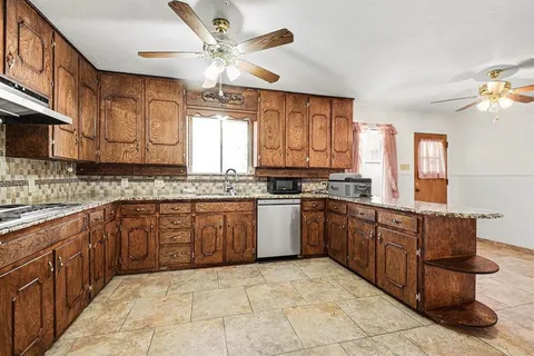 a large kitchen with stainless steel appliances granite countertop a sink and cabinets
