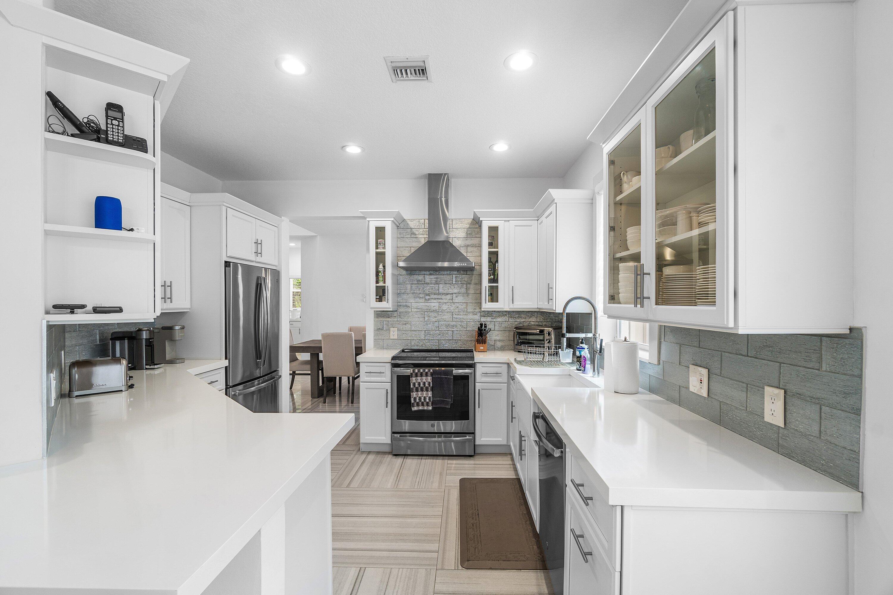2404 Northwest 67th Street Boca Raton, FL 33496 - Photo 8 of 74 a large kitchen with stainless steel appliances lots of counter top space and wooden floor