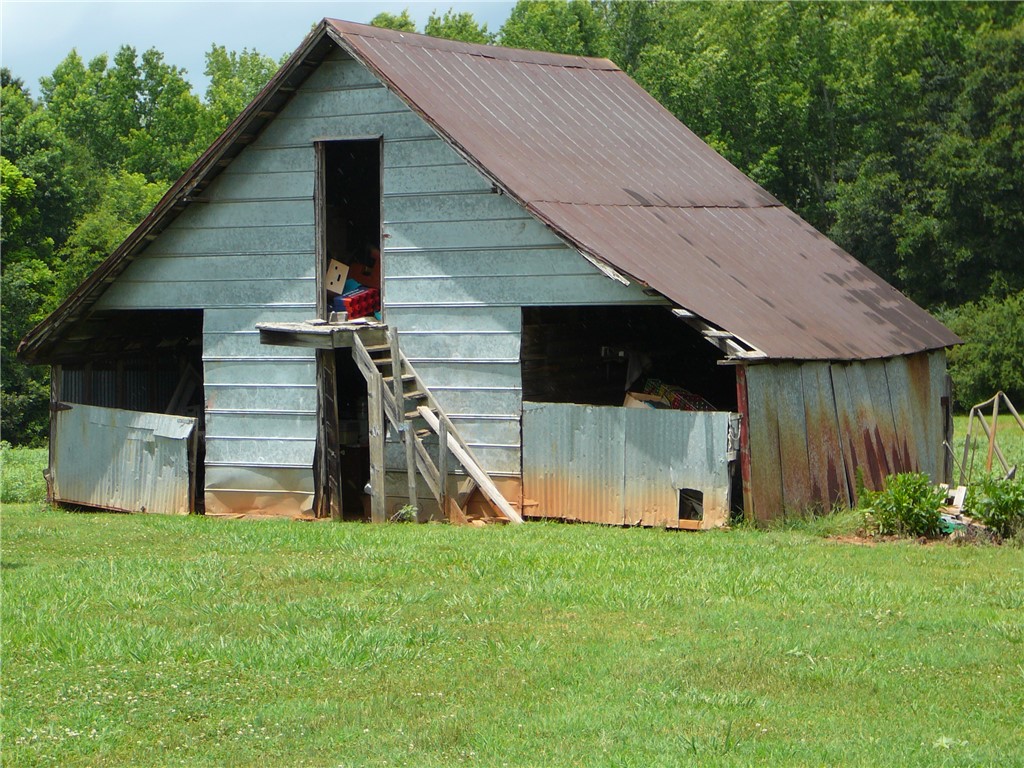 1430 Grady Hall Road Anderson, SC 29626 - Photo 5 of 14 A charming rustic barn with a metal roof nestled in a verdant field, ideal for storage.