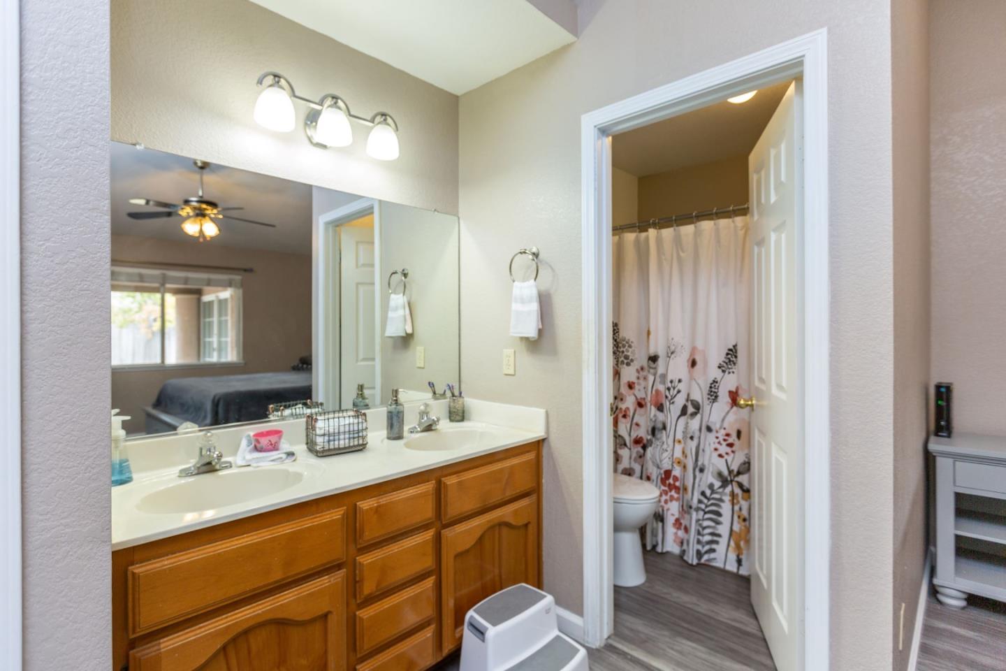2085 Roth Court Turlock, CA 95380 - Photo 19 of 26 a bathroom with double vanity sinks a toilet a shower and a mirror