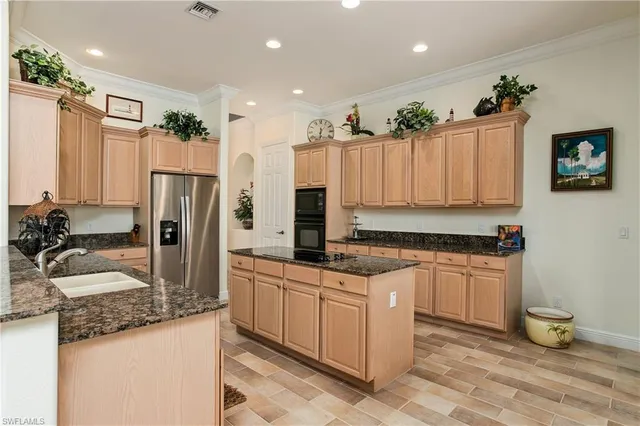 a kitchen with kitchen island granite countertop a sink refrigerator and cabinets