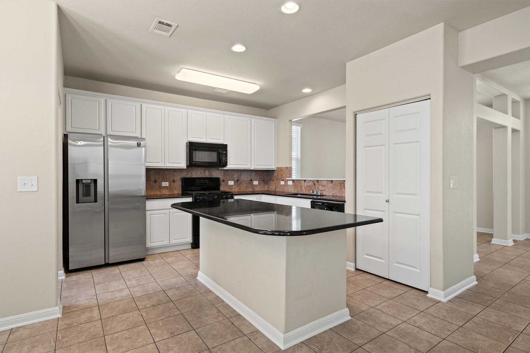 423 Wetzel Kyle, TX 78640 - Photo 14 of 35 Kitchen featuring black appliances, decorative backsplash, white cabinetry, light tile patterned floors, and recessed lighting