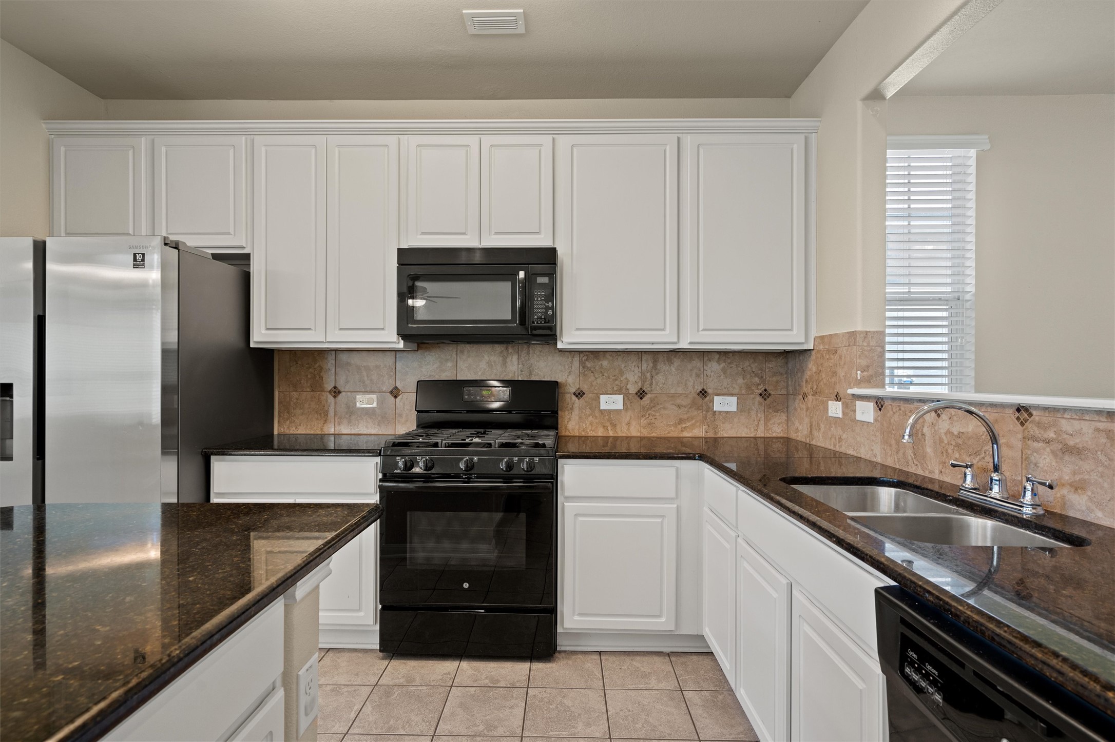 423 Wetzel Kyle, TX 78640 - Photo 15 of 35 Kitchen with white cabinetry, dark stone countertops, black appliances, and decorative backsplash