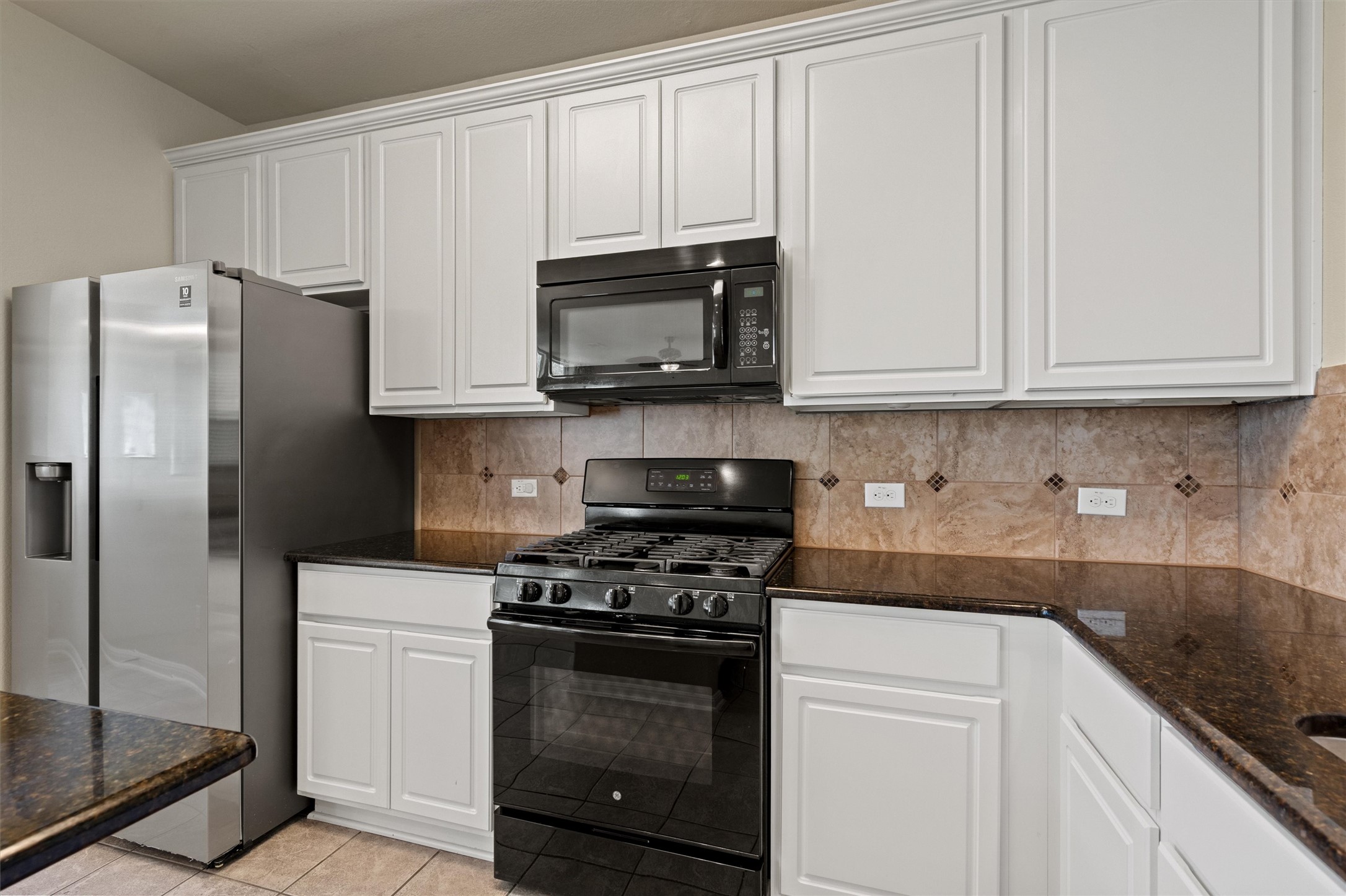 423 Wetzel Kyle, TX 78640 - Photo 16 of 35 Kitchen with black appliances, white cabinetry, and dark stone countertops