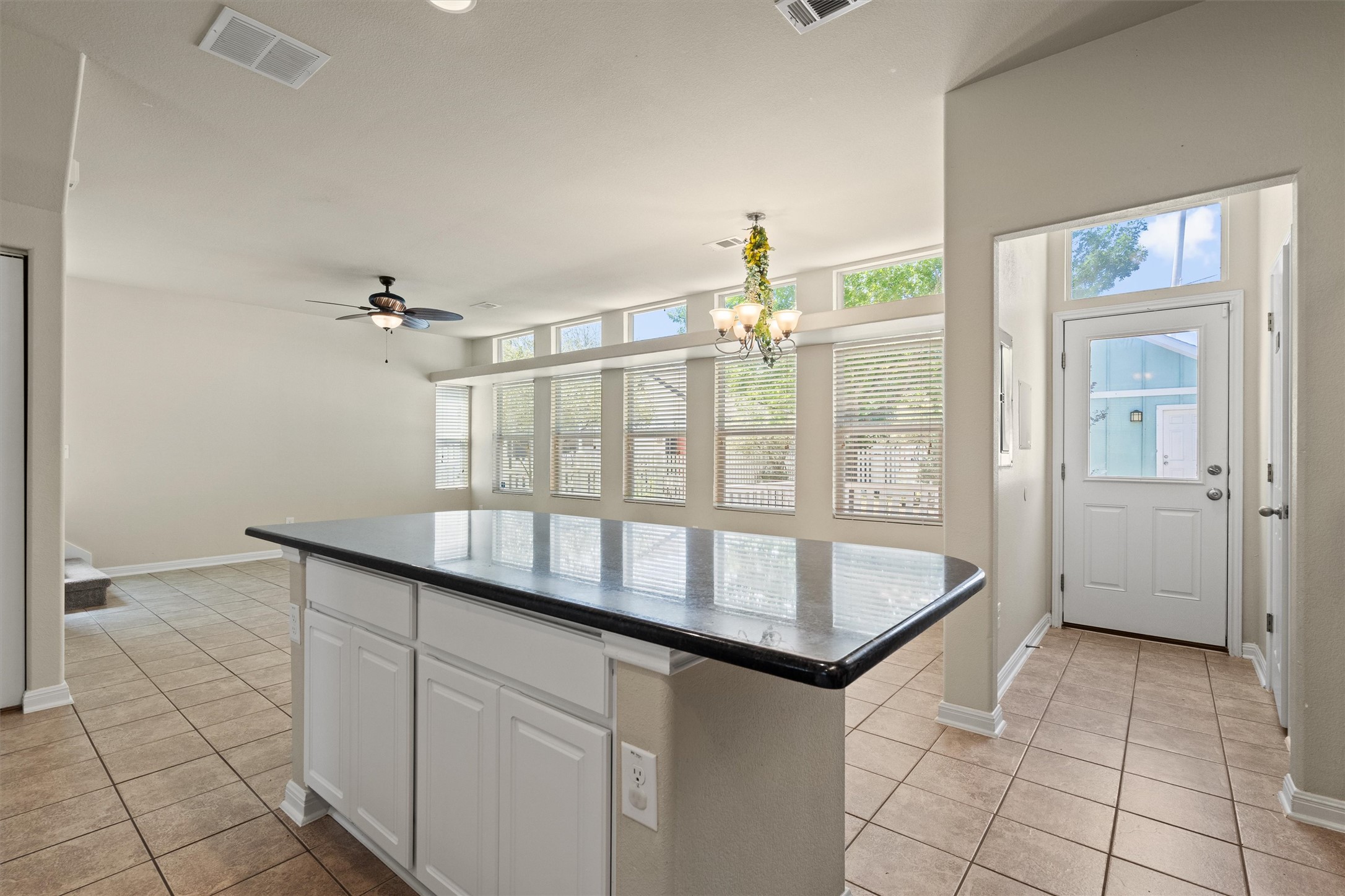 423 Wetzel Kyle, TX 78640 - Photo 18 of 35 Kitchen featuring dark countertops, a kitchen island, light tile patterned flooring, white cabinets, and ceiling fan