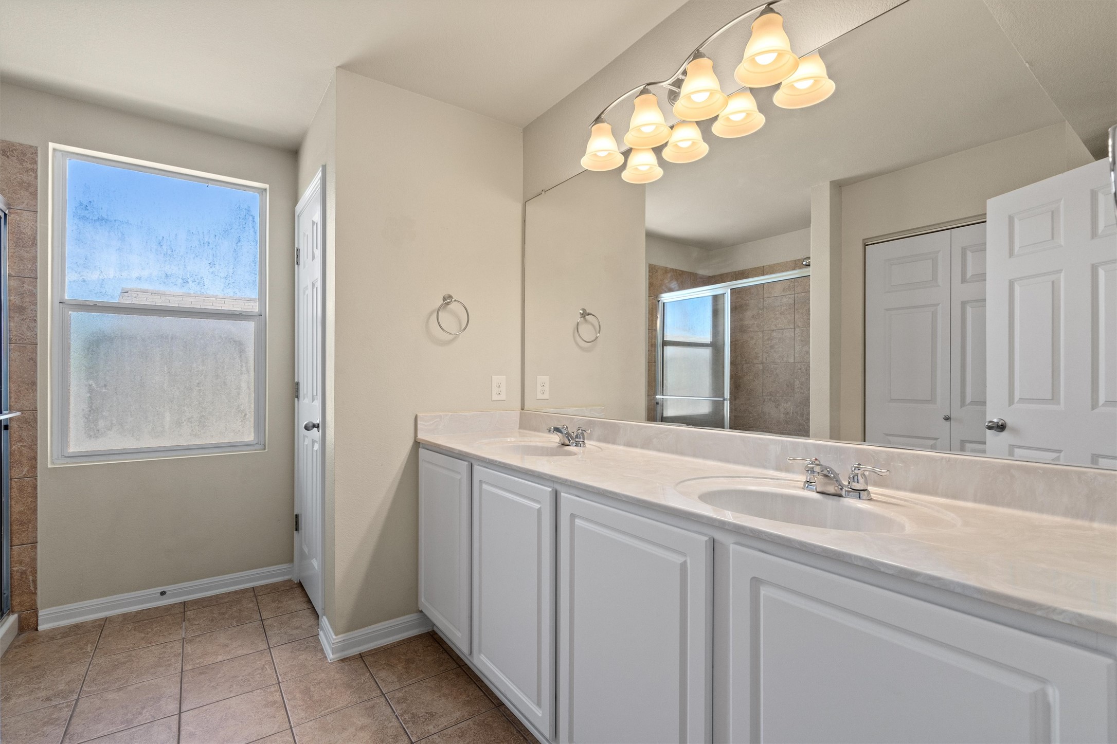 423 Wetzel Kyle, TX 78640 - Photo 23 of 35 Bathroom featuring double vanity, light tile patterned floors, a shower stall, and a closet
