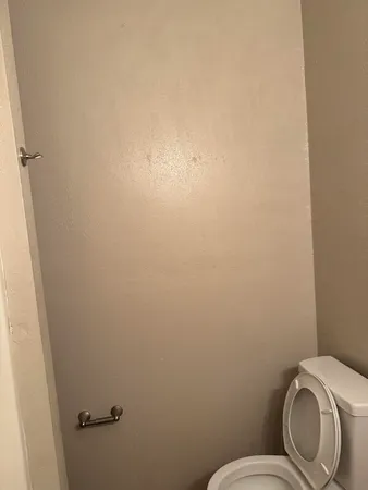 a white toilet sitting next to a white wall