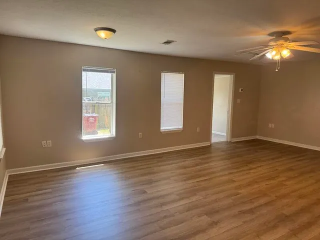 an empty room with wooden floor and windows