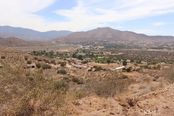 a view of a dry yard with mountains in the background