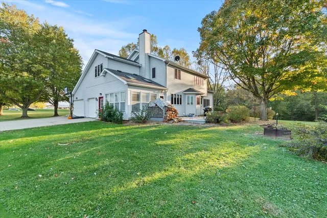 a view of a house with a big yard potted plants and large tree