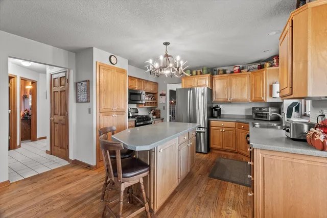 a kitchen with granite countertop a refrigerator a stove a sink a dining table and chairs with wooden floor