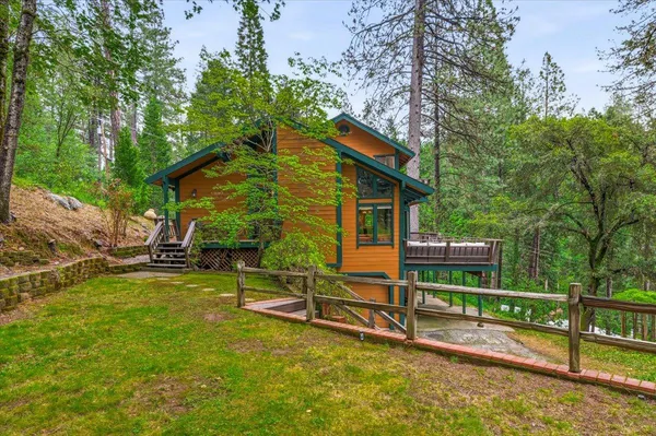 a view of backyard with wooden fence and large trees