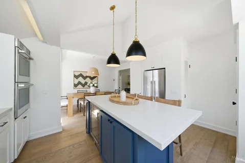 a kitchen with stainless steel appliances a dining table chairs and white cabinets