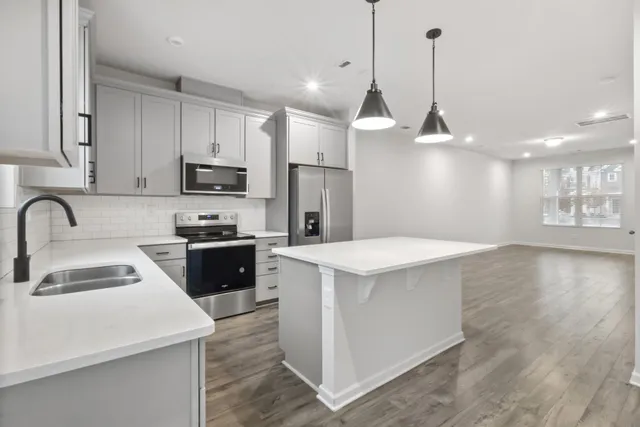 a kitchen with stainless steel appliances a sink a stove a refrigerator a center island and cabinets