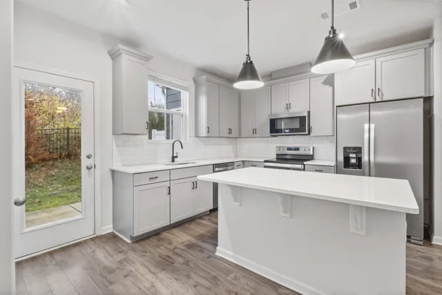 a kitchen with kitchen island a sink stainless steel appliances and window