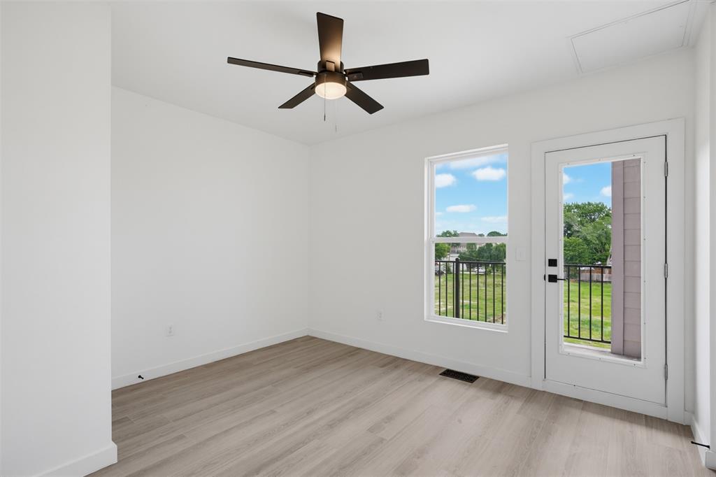 512 South O Connor Road Irving, TX 75060 - Photo 18 of 21 Room featuring wood-finish flooring, a ceiling fan with integrated lighting, a window, and a glass-paneled door opening to an exterior balcony with black metal railings